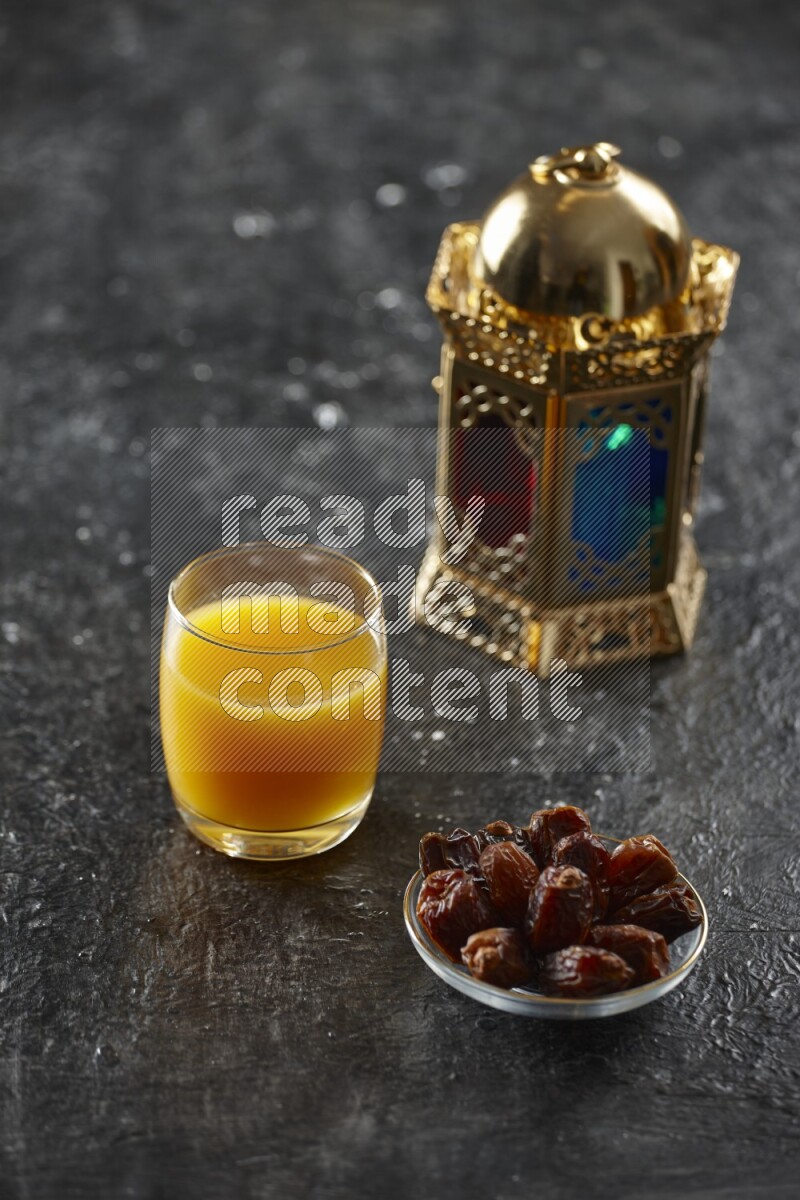 A golden lantern with different drinks, dates, nuts, prayer beads and quran on textured black background