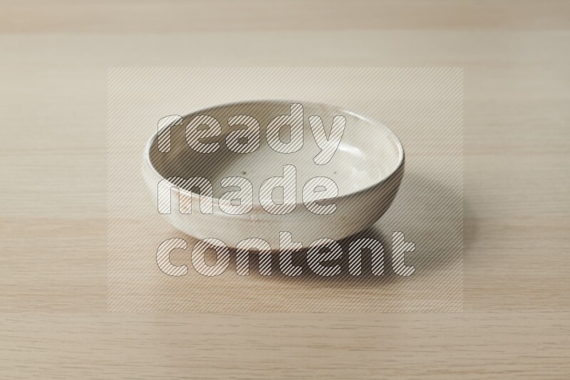 A beige pottery bowl on light wooden background