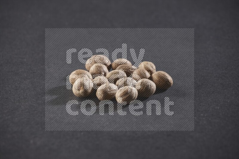 A bunch of whole nutmeg seeds on a black flooring