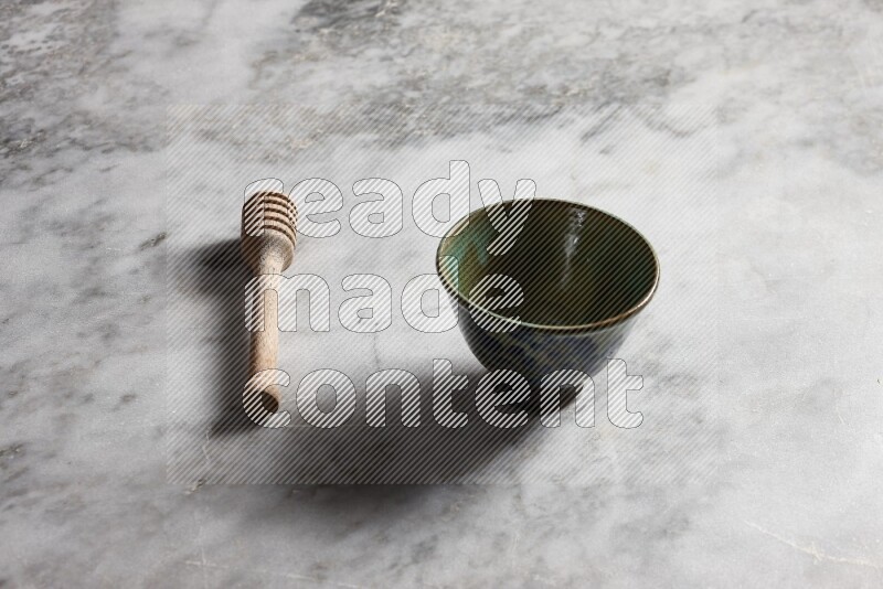Decorative pottery bowl with wooden honey dipper on the side on grey marble background