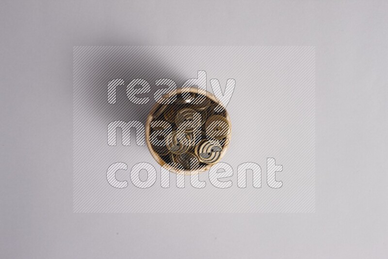 Colored buttons in a beige pottery bowl on grey background
