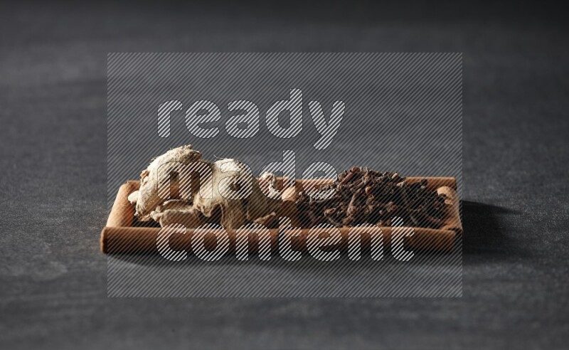 2 squares of cinnamon sticks full of cloves and dried ginger on black flooring