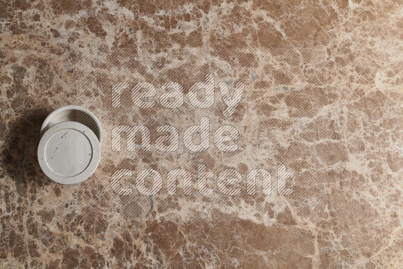 A pottery cup on beige marble background