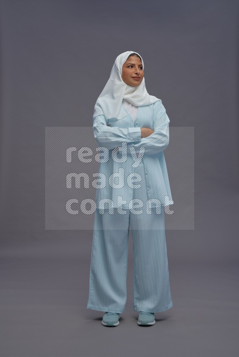 Saudi woman wearing hijab clothes standing with crossed arms on gray background