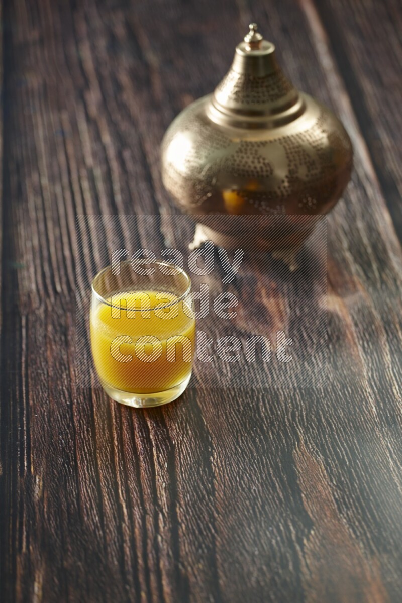 A golden lantern with different drinks, dates, nuts, prayer beads and quran on brown wooden background
