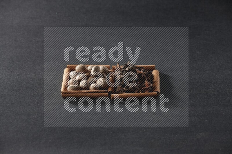 2 squares of cinnamon sticks full of nutmeg and star anise on black flooring