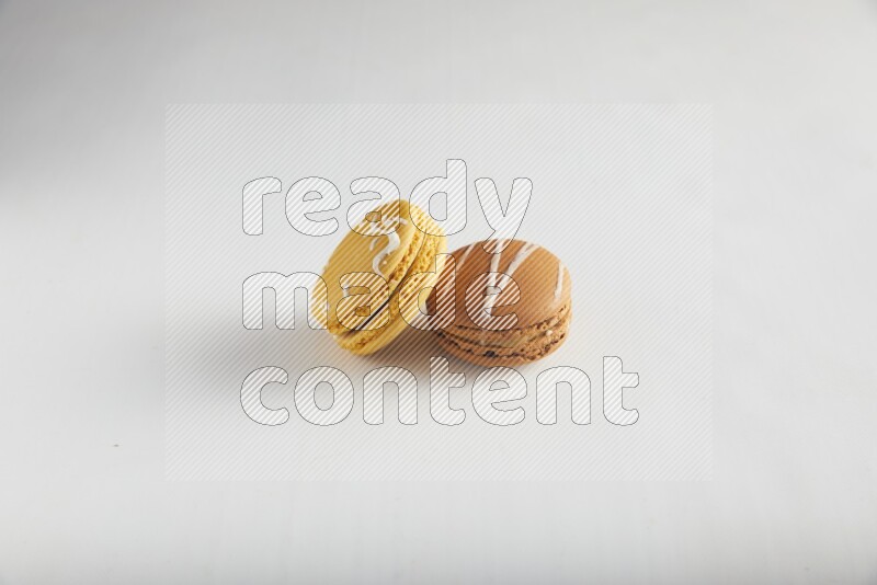 45º Shot of of two assorted Brown Irish Cream, and Yellow Piña Colada macarons on white background