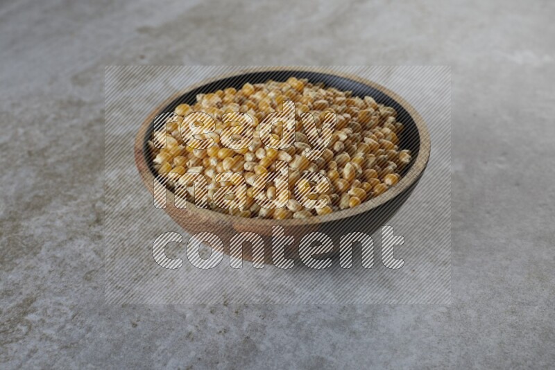 corn kernel in a wooden bowl on a grey textured countertop