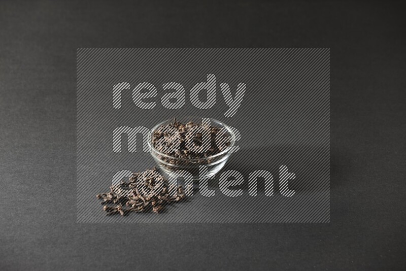 A glass bowl full of cloves on a black flooring