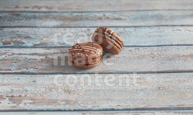 45º Shot of two Brown white  Chocolate Caramel macarons on light blue wooden background