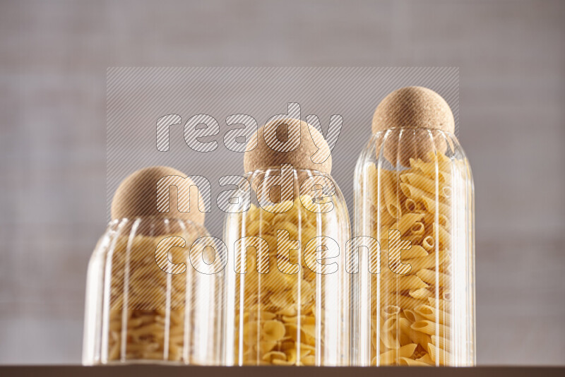 Raw pasta in glass jars on beige background