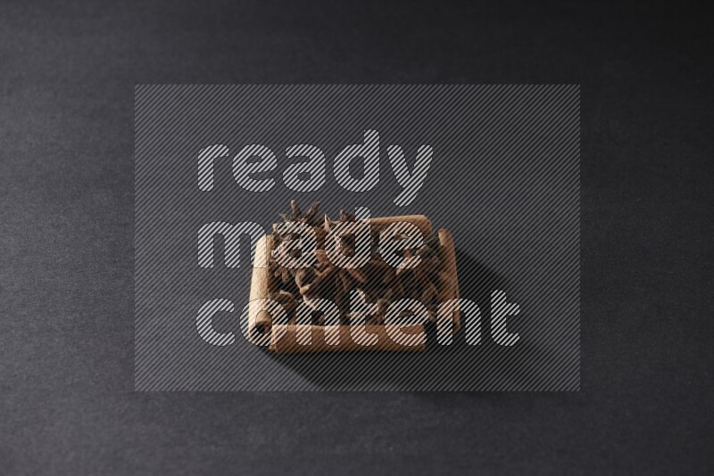 أربعة من أعواد القرفة مكونة شكل مربع بداخلها يانسون نجمي علي خلفية سوداء