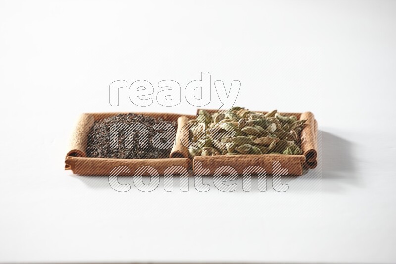 2 squares of cinnamon sticks full of cardamom and black tea on white flooring