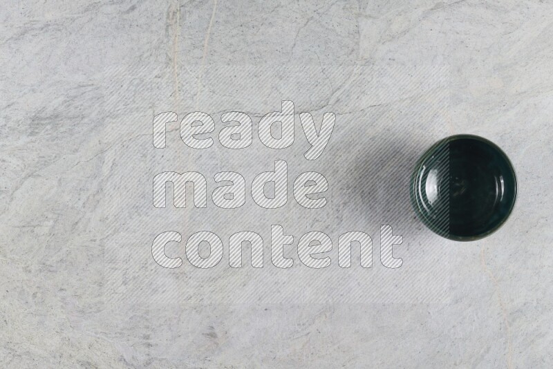 A dark green pottery bowl on grey marble background