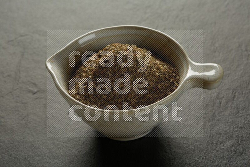 white ceramic round sauce bowl filled with herbs on grey textured countertop