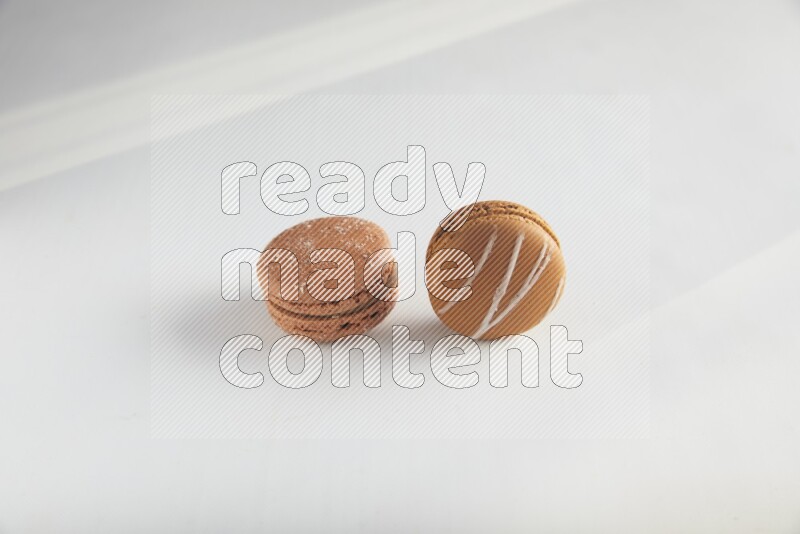 45º Shot of of two assorted Brown Irish Cream, and Brown Hazelnuts macarons on white background