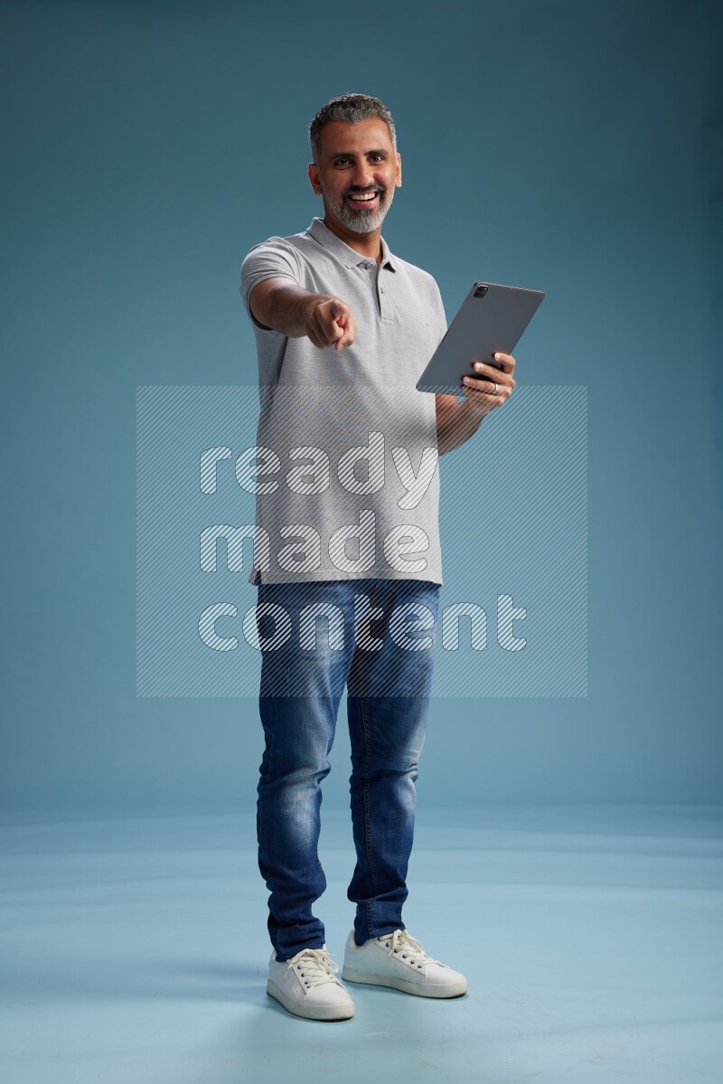 Man Standing working on tablet on blue background