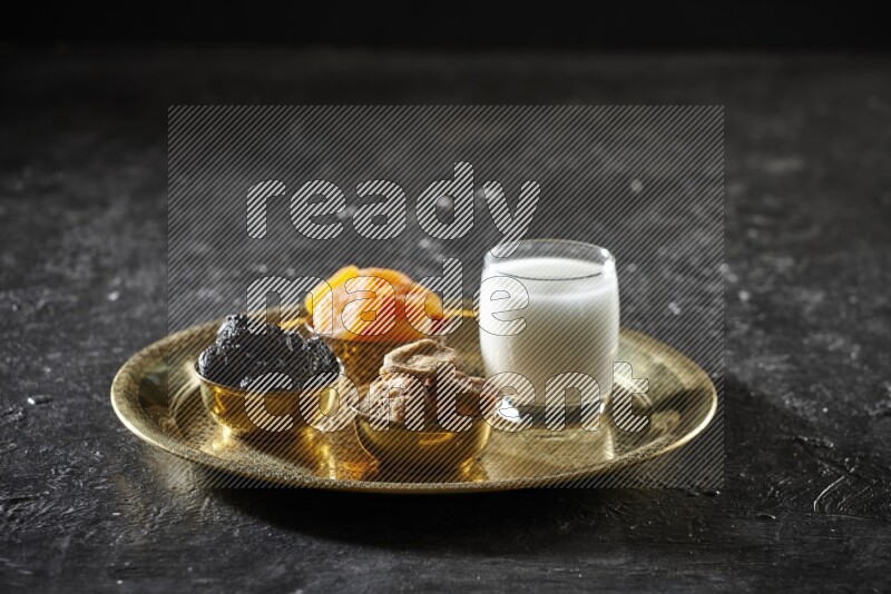 Dried fruits in metal bowls with sobya on a tray in dark setup