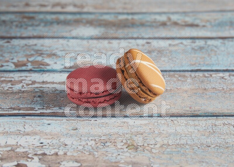 45º Shot of of two assorted Brown Irish Cream, and Pink Raspberry macarons on light blue background