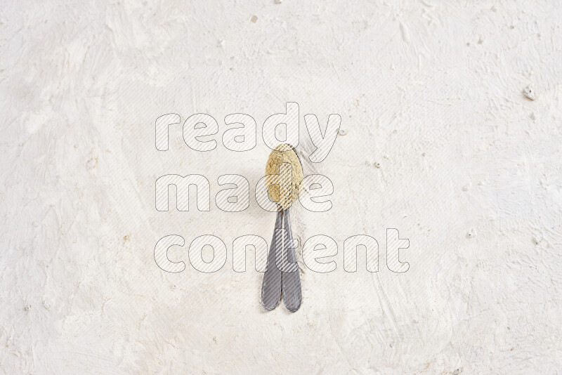 Two metal spoons full of ground ginger powder on white background