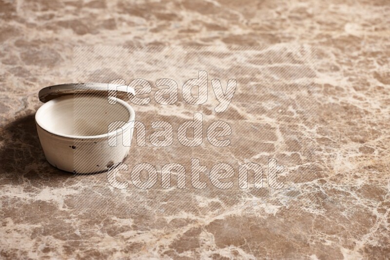 A white pottery bowl on beige marble background