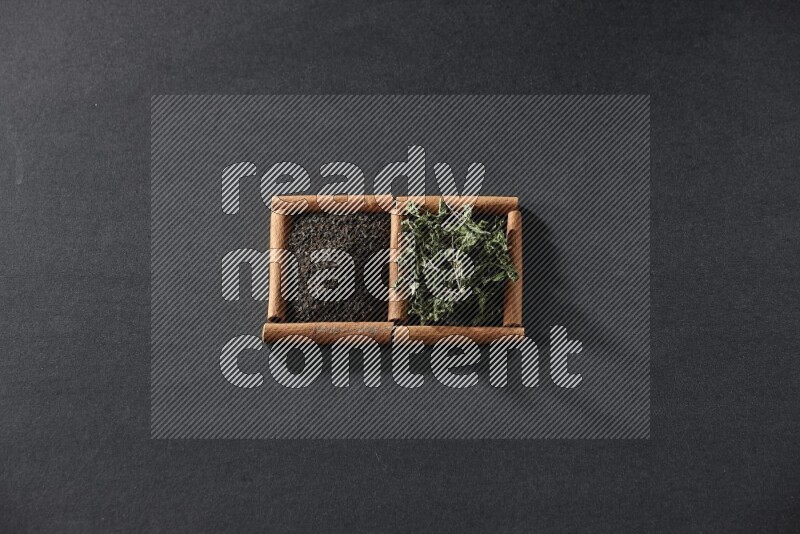 مربعان من أعواد القرفة ممتلئان بالشاي والنعناع المجفف علي خلفية سوداء