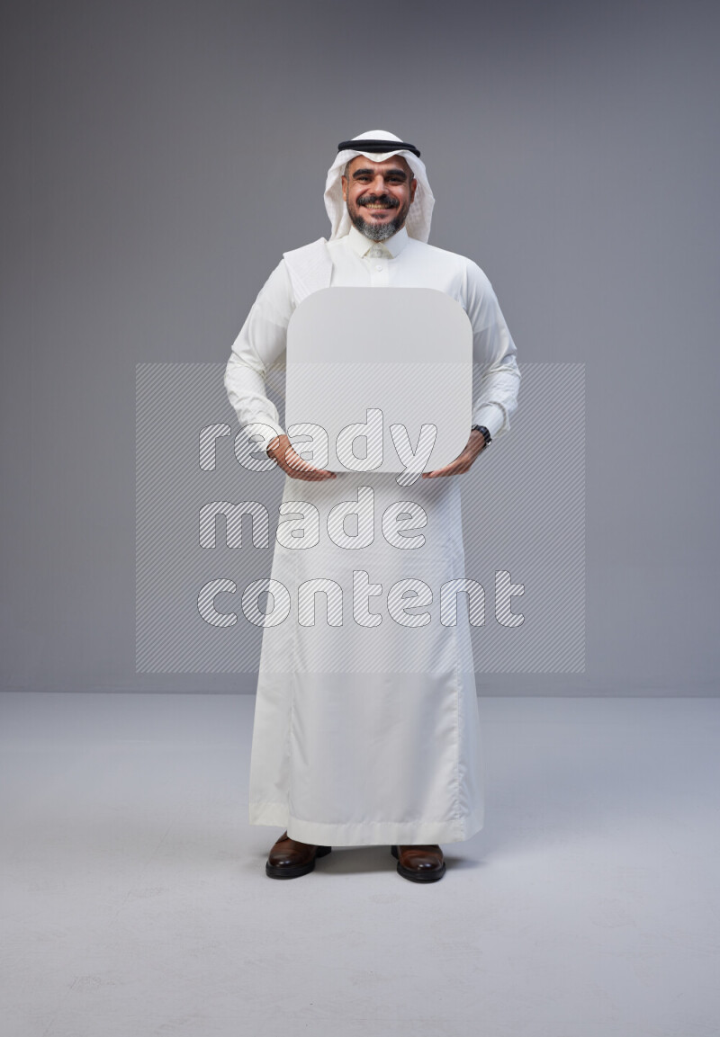 Saudi man Wearing Thob and white Shomag standing holding social media sign on Gray background
