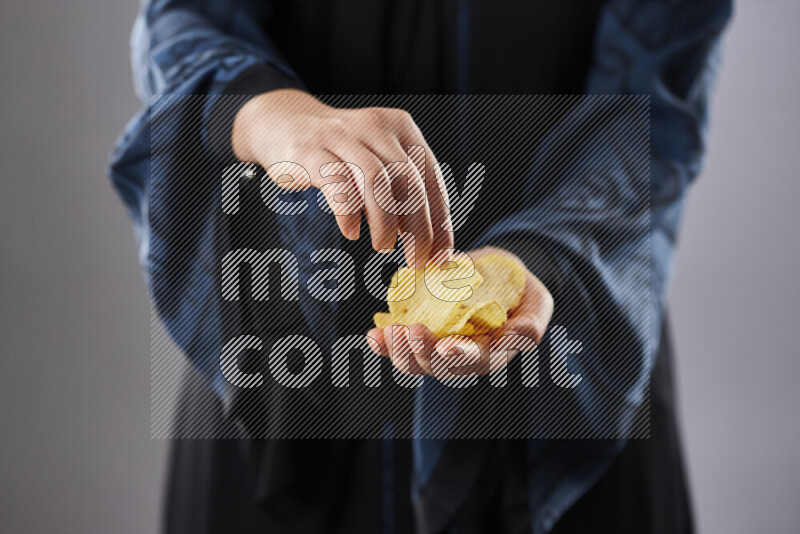 Woman in abaya holding different kinds of snacks in different positions