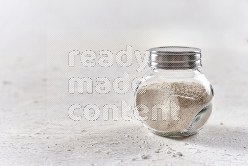 A glass jar full of onion powder on white background