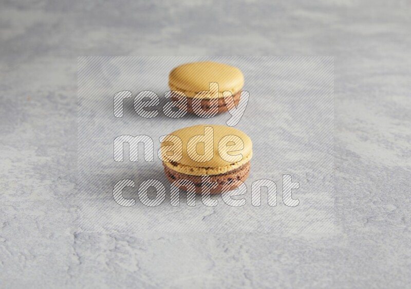 45º Shot of two Yellow and Brown Chai Latte macarons r on white  marble background