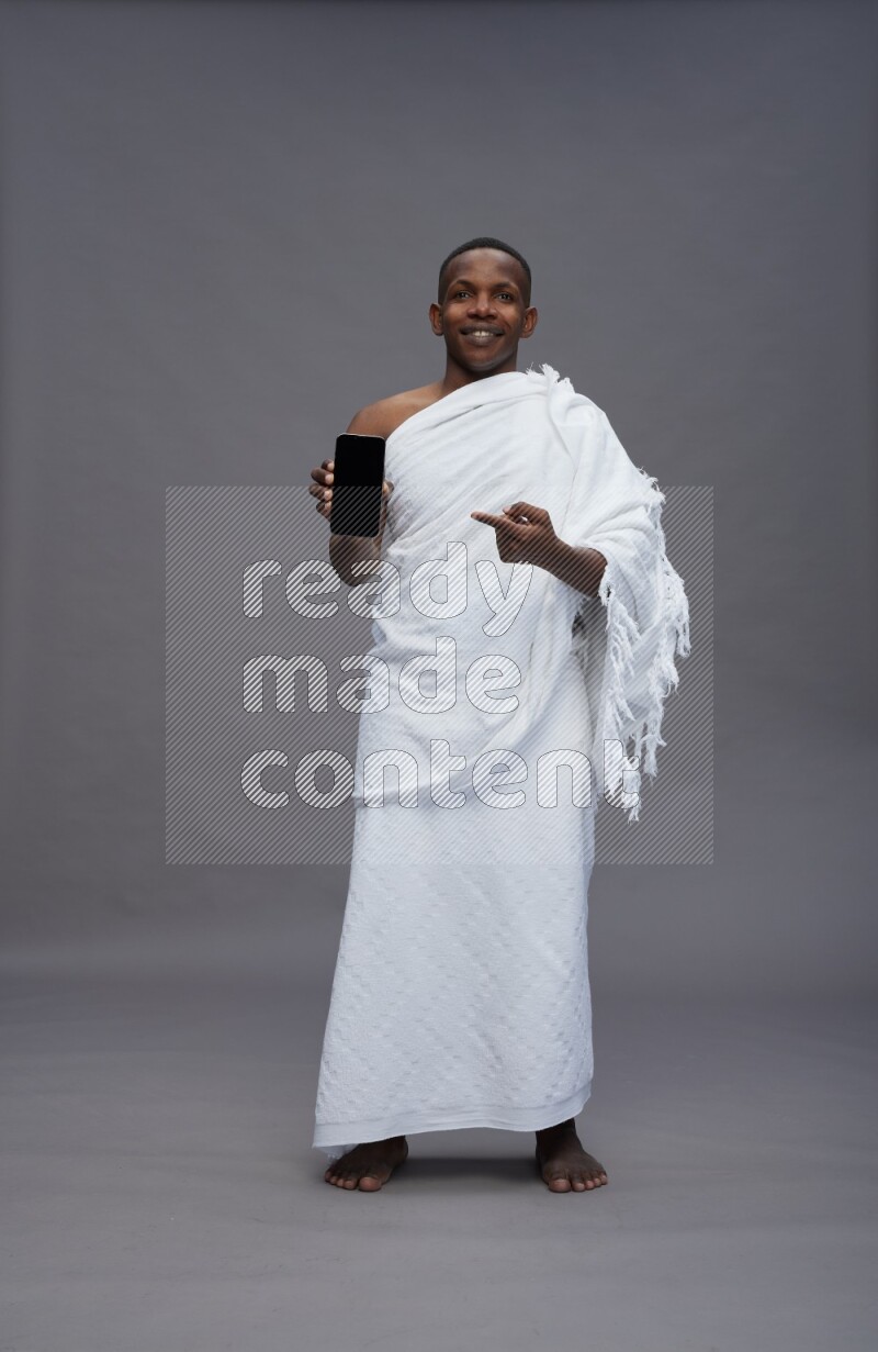 A man wearing Ehram Standing showing phone to camera on gray background