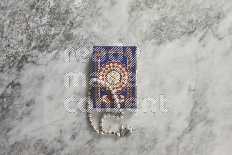 Quran with a prayer beads on grey marble background