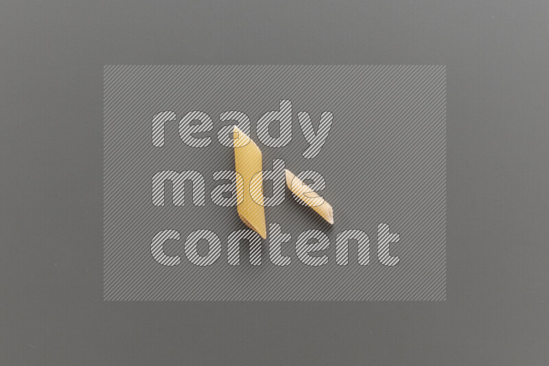 Penne pasta with other types of pasta on grey background