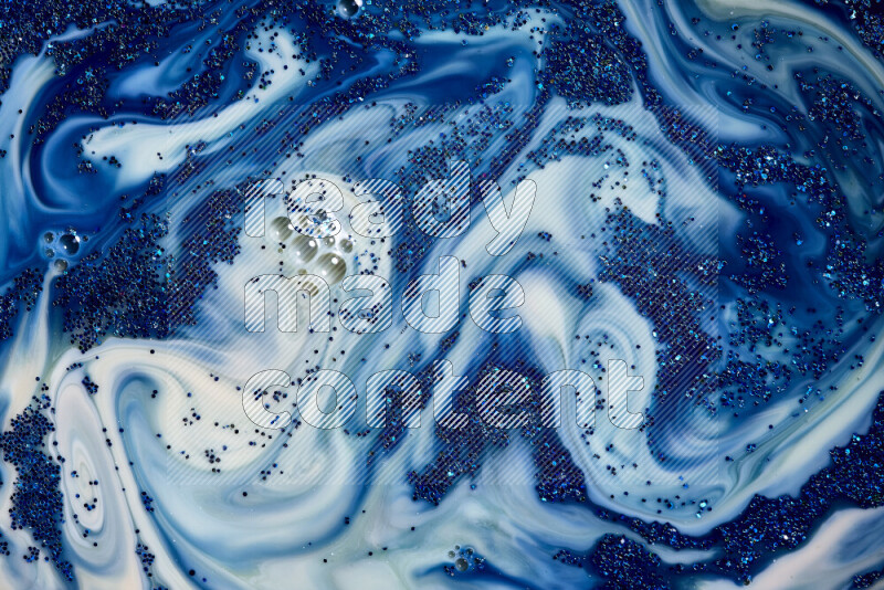A close-up of sparkling blue glitter scattered on swirling blue and white background