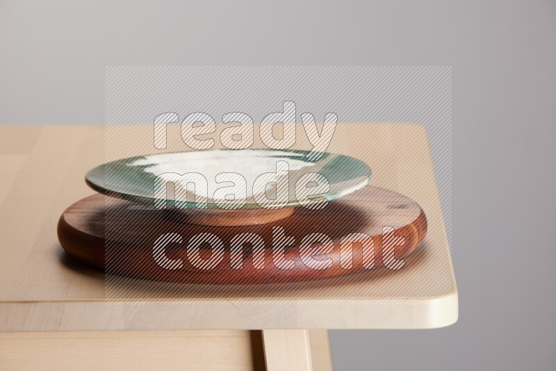 multi-colored pottery Plate placed on a dark colored wooden tray on the edge of wooden table