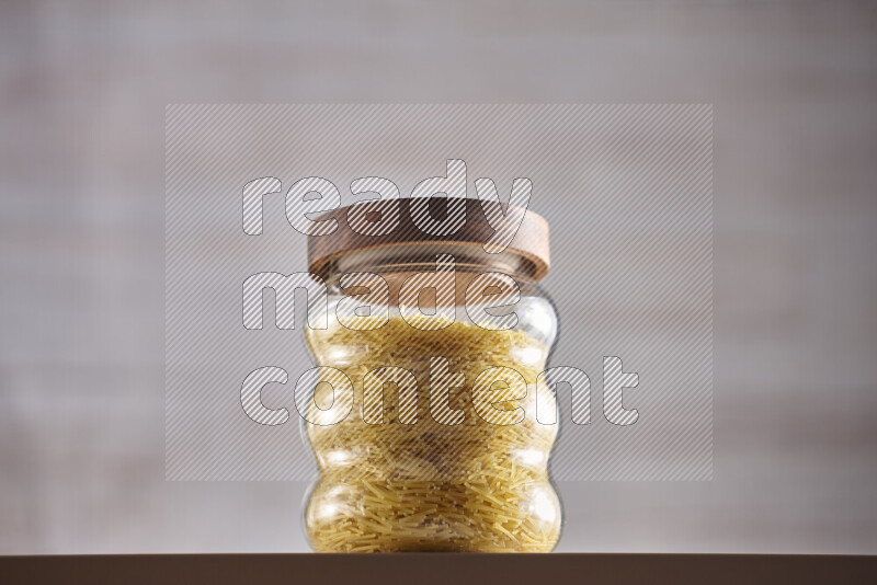 Raw pasta in glass jars on beige background