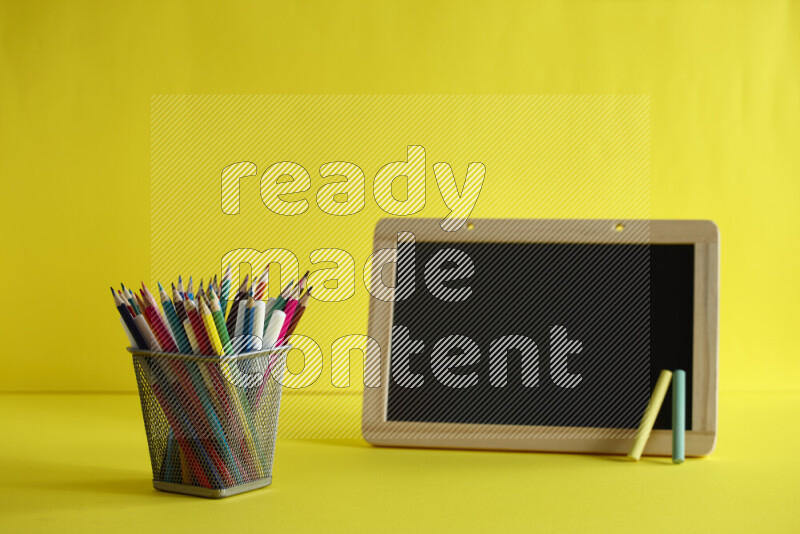 A blackboard with different school supplies on yellow background