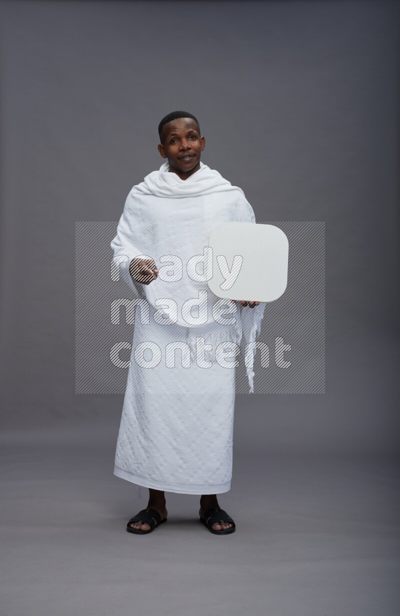 A man wearing Ehram Standing holding social media sign on gray background