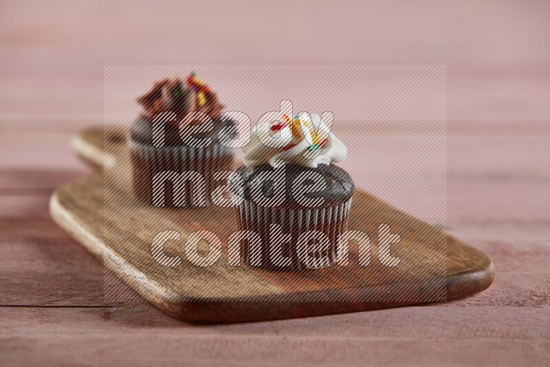 Chocolate mini cupcake topped with cream on a wooden board