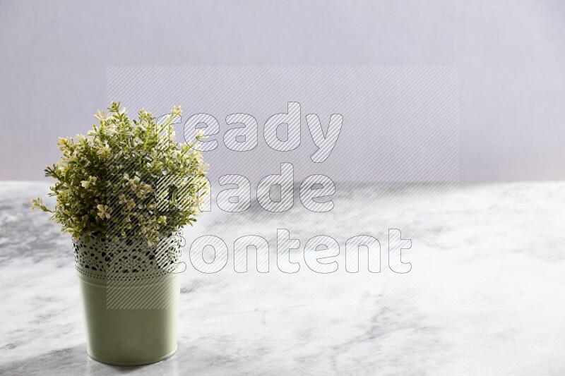 Artificial plant in green decorative pot on grey marble background