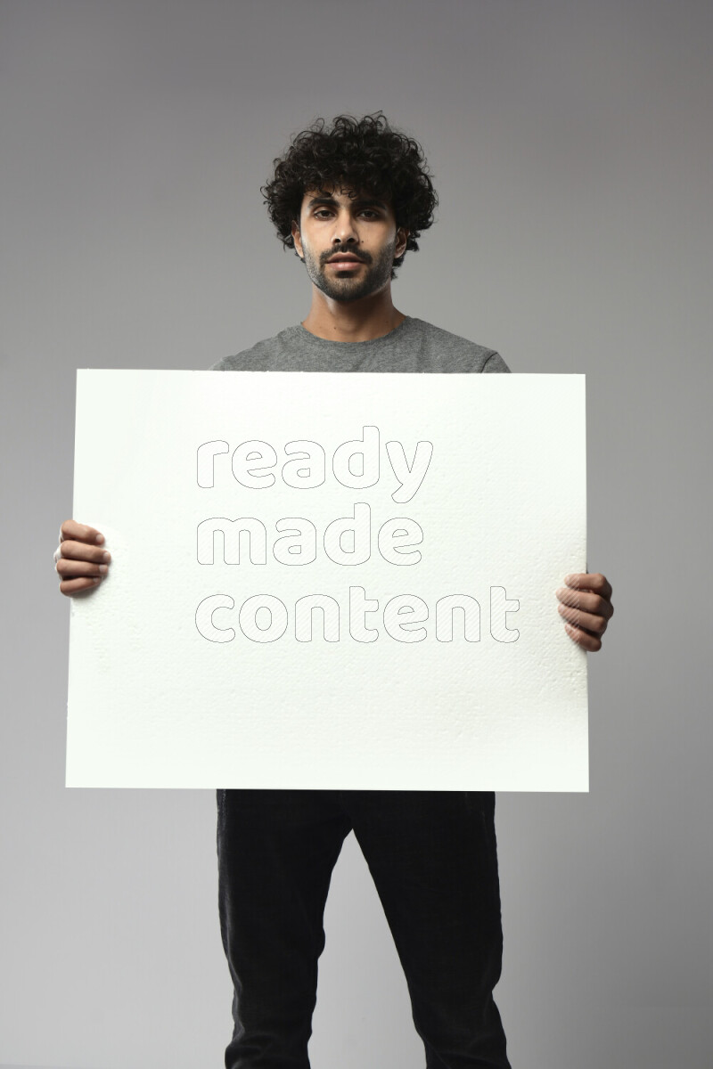 رجل يرتدي ملابس كاجوال يحمل لوحة بيضاء علي خلفية بيضاء