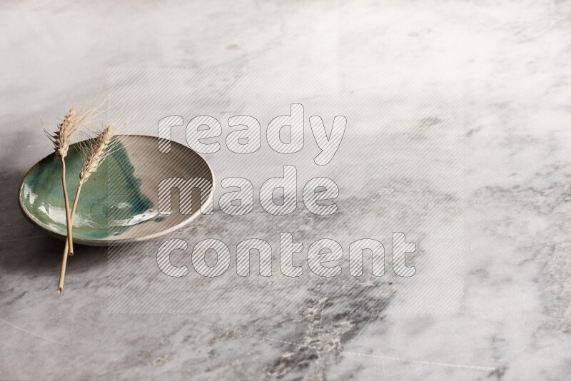 سنابل من القمح علي طبق فخاري متعدد الألوان علي خلفية من الرخام الرمادي