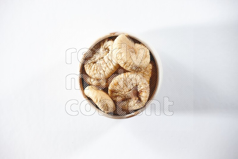 A beige ceramic bowl full of dried figs on a white background in different angles
