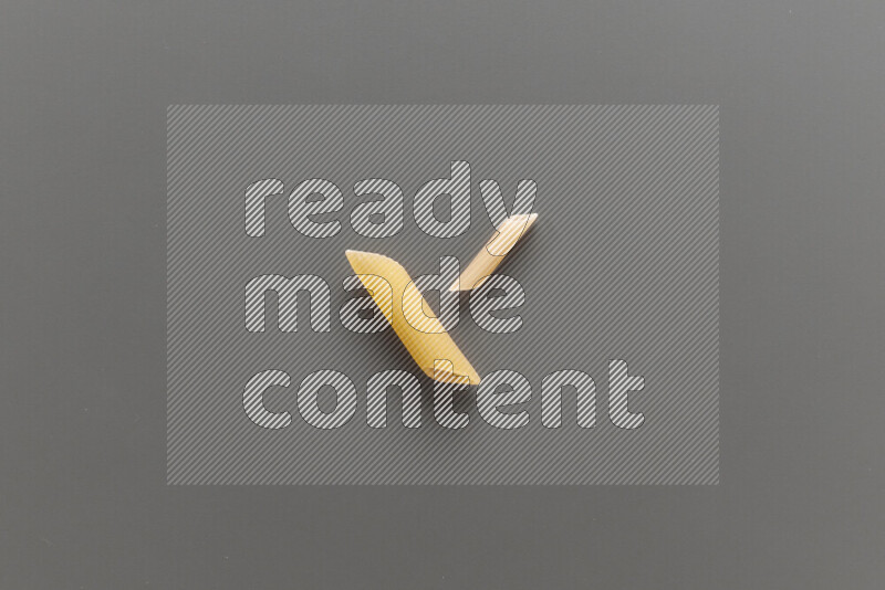 Penne pasta with other types of pasta on grey background