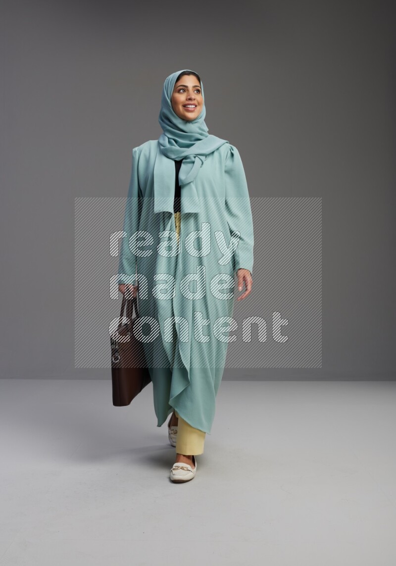Saudi Woman wearing Abaya standing holding bag on Gray background