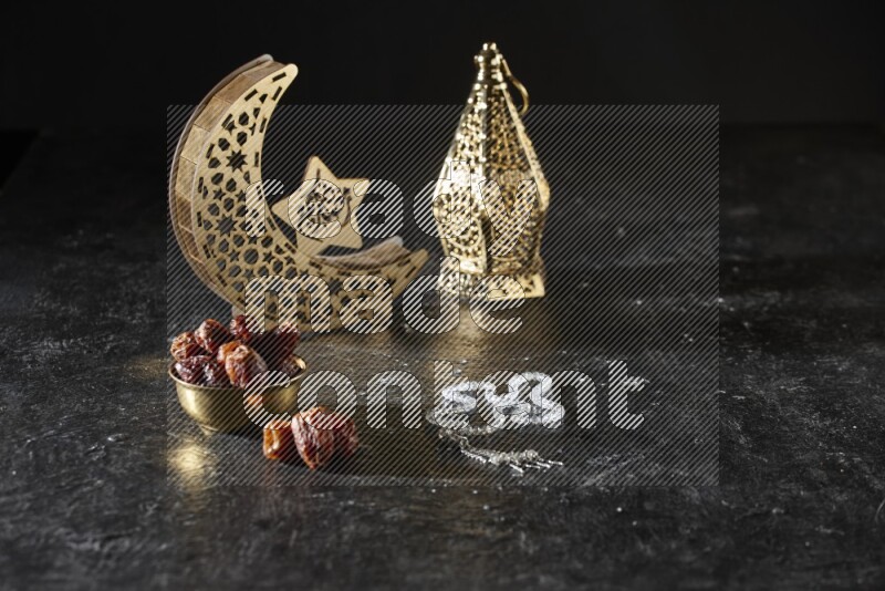 Dates in a metal bowl with prayer beads beside golden lanterns in a dark setup