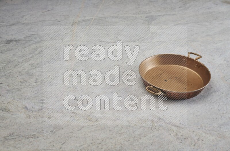 A small copper pan on grey marble background