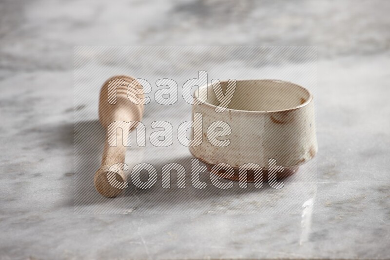 Beige pottery bowl with wooden honey dipper on the side on grey marble background