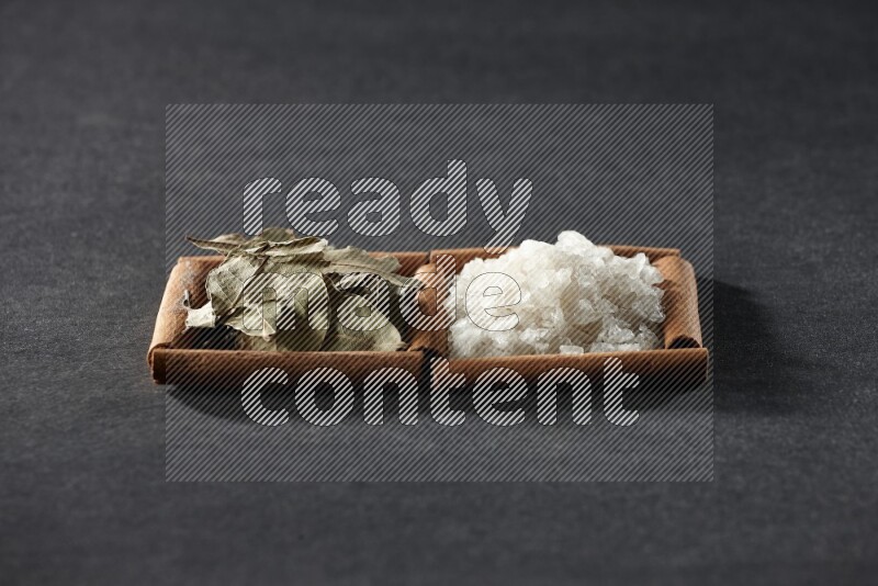 2 squares of cinnamon sticks full of salt and bay laurel on black flooring