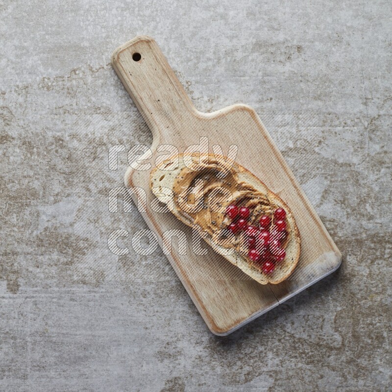 open faced peanut butter sandwich with cranberries and chia seeds grey textured background